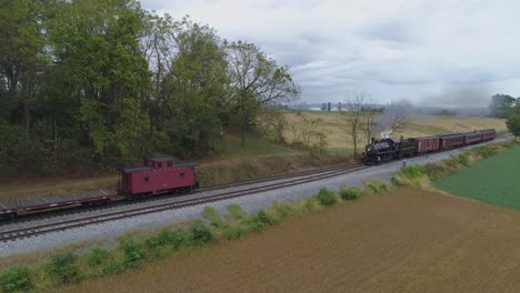 Luftaufnahme-Eines-Personenzuges-Mit-Dampflokomotive,-Der-Langsam-Auf-Einem-Abstellgleis-Mit-Rauch-Und-Dampf-Fährt