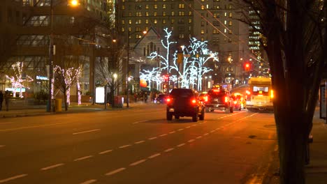 Coches-Circulando-Por-Una-Calle-Con-Luces-Exteriores-En-Los-árboles-En-El-Centro-De-Vancouver-Al-Atardecer-En-Invierno