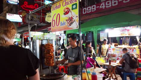 Handheld-scenes-of-the-tourists-are-walking-around-Khao-San-Road-at-night-time-famous-which-each-year-tourists-from-many-countries-came-to-visit-in-Bangkok,-Thailand