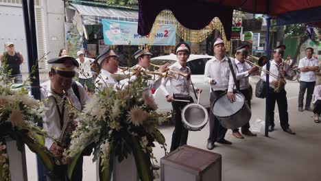 Una-Banda-De-Música-Vestida-Con-Uniforme-Colonial-Francés-Toca-Música-A-Todo-Volumen,-Un-Importante-Ritual,-En-Un-Funeral-En-Una-Estrecha-Calle-Urbana-De-Vietnam