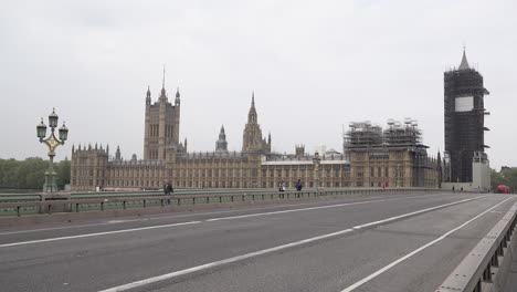 Varias-Personas-Caminan-Frente-A-Las-Casas-Del-Parlamento-Mientras-Cruzan-Un-Puente-Desierto-De-Westminster-Durante-El-Brote-De-Coronavirus