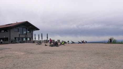 La-Gente-Se-Relaja-En-La-Meseta-Junto-A-Un-Restaurante-En-Un-Día-Nublado,-Hornisgrinde,-Alemania