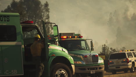 Bomberos-Estadounidenses-Que-Llegan-Al-área-Del-Desastre-Con-Humo-De-Incendios-Forestales-En-El-Fondo