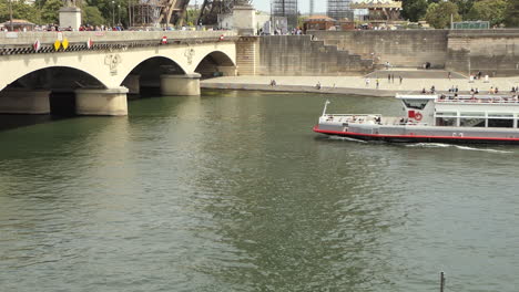 Excursión-En-Barco-Por-El-Río-Sena-Con-Turistas-Pasando-Por-Debajo-Del-Puente-Iena-Frente-A-La-Torre-Eiffel