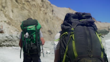 Close-fallowing,-tracking-shot-of-backpackers-as-hiking-in-the-mountains-on-a-bright-sunny-day