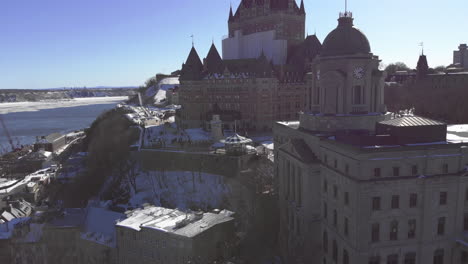 Majestuoso-Chateau-Frontenac-Se-Encuentra-Cubierto-De-Nieve-En-La-Cima-De-Una-Colina,-Antena-De-Drones