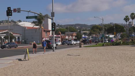 Ein-Paar-Geht-Den-Pacific-Coast-Highway-Entlang,-Während-Es-Am-Broadway-In-Laguna-Beach,-Kalifornien,-Vorbeifährt