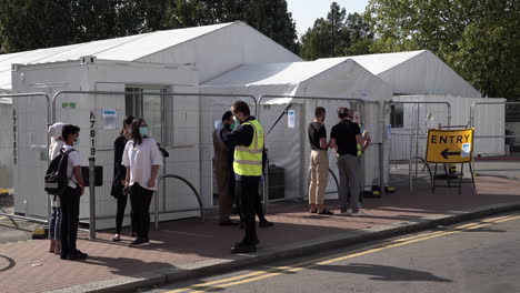 Two-men-in-protective-face-masks-are-turned-away-by-Serco-staff-for-not-having-an-appointment-at-an-appointment-only-Covid-19-testing-centre