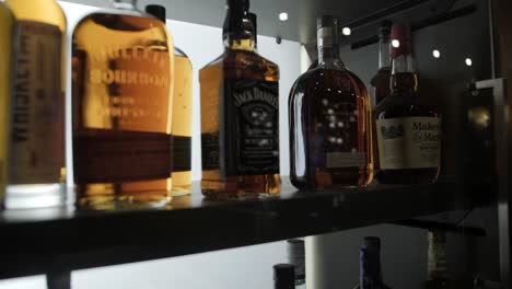 Various-backlit-liquor-bottles-on-a-display-case-shelf