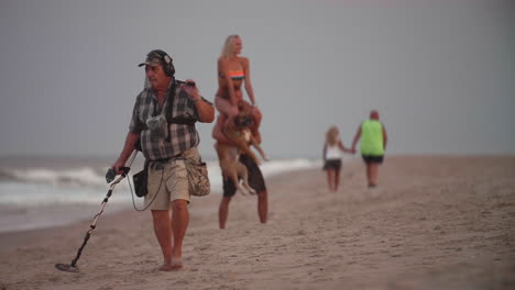 Man-with-metal-detector-searching-along-shoreline