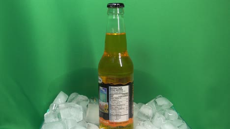 1-3-Botella-De-Vidrio-De-Bebida-De-Champán-Kola-Con-Sabor-A-Marca-Grace-Que-Gira-360-Grados-En-Un-Recipiente-Lleno-De-Hielo-Frente-A-Una-Pantalla-Verde