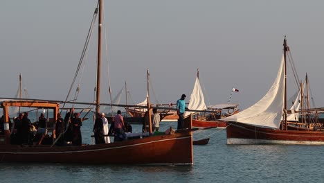 A-view-of-traditional-wooden-boat-known-as-Dhow,-carrying-a-group-of-local-people-singing-and-dancing-at-Katara-Village,-Doha,-Qatar-on-the-occasion-of-Dhow-Festival