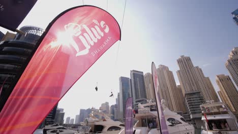 Tourists-in-Dubai-ride-overhead-on-wired-ziplines-in-Dubai-Marina,-United-Arab-Emirates