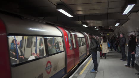 Concurrida-Estación-De-Metro-De-Londres,-Pasajeros-Y-Trenes-Que-Llegan-A-La-Plataforma-Durante-Las-Vacaciones-De-Navidad,-Vista-Amplia-60fps