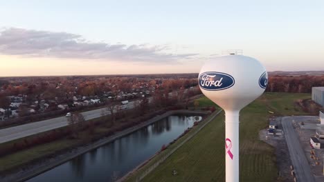 Torre-De-Agua-De-La-Planta-De-Estampado-De-Ford-Woodhaven-En-Wyandotte,-Michigan,-Con-Vistas-A-La-Concurrida-Carretera-Al-Atardecer---Tiro-De-Arco-Aéreo