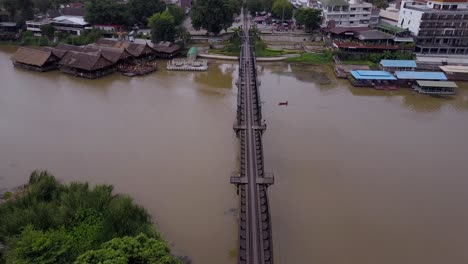 Toma-Aérea-De-Drones-Cruzando-El-Puente-Sobre-El-Río-Kwai,-Ferrocarril-De-La-Muerte-De-Tailandia,-Kanchanaburi,-Tailandia