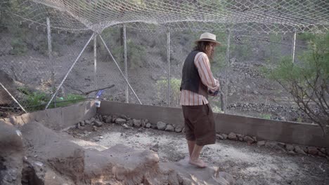 young-hippie-man-feed-his-chicken-walking-barefoot-downstairs