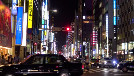 La-Vista-De-La-Famosa-Calle-Comercial-Ginza,-Autos-Y-Gente-Caminando-Por-La-Noche