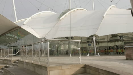 Pan-right-to-left-from-a-sculpture-outside-Dynamic-Earth-to-the-front-of-the-Dynamic-Earth-building-on-a-sunny-day-in-Edinburgh,-Scotland