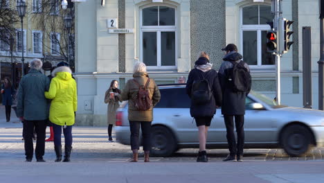 Fußgänger-Warten-Am-Zebrastreifen,-Um-Die-Straße-Zu-überqueren,-Während-Autos-Auf-Der-Straße-Fahren