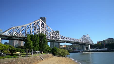 Iconic-view-of-Brisbane's-Story-Bridge,-looking-back-up-river-towards-the-City-as-the-famous-Citycat-ferries-cruise-the-Brisbane-River