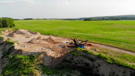 Aerial-boom-shot-from-a-drone-of-quarry,heavy-machinery-and-green-meadow-in-pomeranian-district-in-Poland-showing-contrast-between-nature-and-industry