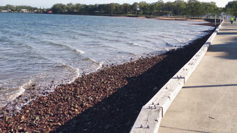 Toma-Panorámica-Lenta-De-Las-Olas-Del-Océano-Y-El-Paseo-Marítimo-En-El-Embarcadero-De-Woody-Point-En-Una-Mañana-Fría-Y-Soleada