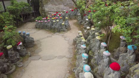 Small-Buddha-statues-with-woolly-hat-on-a-path-of-the-Daisho-in-Buddhist-temple-site-on-the-on-Miyajima-Island,-prefecture-of-Hiroshima