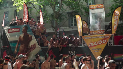 One-of-the-trucks-at-the-Gay-Pride-march-showcasing-a-person-taking-a-shower-on-top-of-it-and-people-dancing-next-to-it