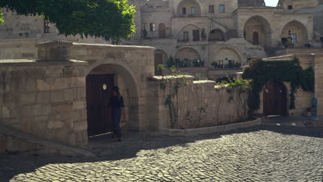 Woman-walks-on-a-sunny-cobblestone-street-through-the-ancient-city-of-Goreme,-Turkey