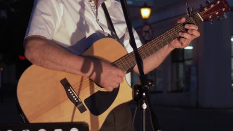 Músico-Con-Una-Camisa-Blanca-Toca-Una-Guitarra-Acústica-Por-La-Noche