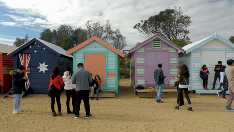 Tourists-walking-and-taking-photo-at-Brighton-Bathing-Boxes,-Melbourne,-Australia