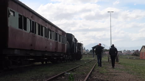 Zwei-Jungen-Im-Teenageralter,-Die-Neben-Einem-Eisenbahnwaggon-Und-Einer-Stillgelegten-Eisenbahnstrecke-Entlanggehen