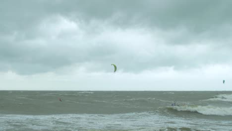 Surfistas-De-Kitesurf-Navegando-En-Las-Grandes-Olas-Del-Mar-Báltico-En-La-Playa-De-Liepaja-Karosta,-Día-De-Otoño-Nublado,-Plano-General