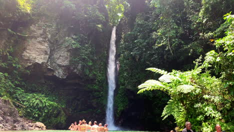 Grupo-De-Turistas-O-Personas-Que-Se-Reúnen-Y-Nadan-Justo-Debajo-De-La-Cascada-De-Agua-Que-Cae-Desde-Lo-Alto