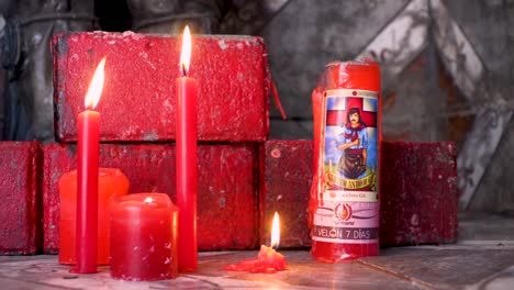 Close-up-shot-of-red-candles-burning-in-Gauchito-Gil-sanctuary,-Argentina