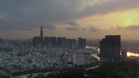 Toma-épica-Del-Amanecer-Con-Drones-De-La-Ciudad-De-Ho-Chi-Minh-Volando-Hacia-Los-Desarrollos-Emblemáticos-Y-Del-Parque-Central-Y-Terminando-Con-El-Desarrollo-Del-Río-Dorado-Con-Sol-Y-Reflejos