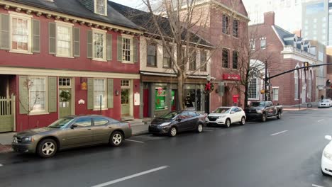 Dolly-shot-in-historic-urban-town-setting-as-traffic-passes-by,-winter,-bare-trees