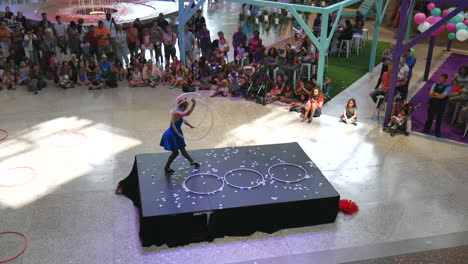 Mujer-Bailando,-Jugando-Al-Aro,-Espectáculo-De-Hula-Hoop,-Evento-Al-Aire-Libre,-Gimnasia,-Vista-De-Entrenamiento-En-La-Arena,-Gente-Y-Niños-Mirando,-Audiencia-Aplaudiendo,-Aplaudiendo,-Acercamiento-Suave