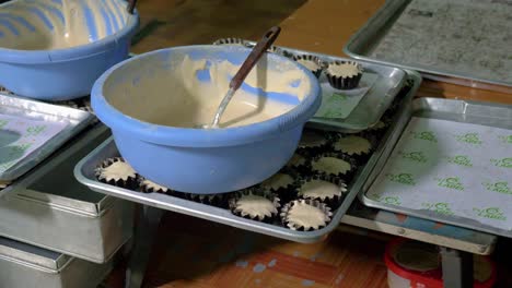 Cuencos-De-Masa-Para-Cupcakes-Sobre-Bandejas-Con-Cupcakes-En-Moldes-Para-Hornear-Listos-Para-Hornear