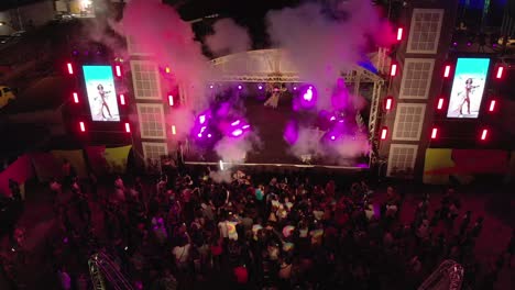 Models-dancing-in-carnival-costumes-on-a-stage-with-fog-and-crowds-in-the-foreground