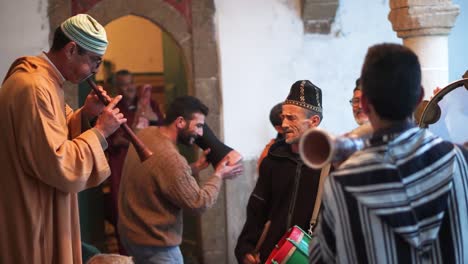 Men-jump-up-and-down-dancing-in-a-trance-as-they-play-drums,-chant,-and-listen-to-the-rhaita-at-a-Sufi-ceremony-in-Essaouira,-Morocco