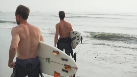 Slow-Motion-120fps---Group-of-surfers-walking-on-the-beach-in-Huanchaco-Peru-checking-the-surf-and-waves