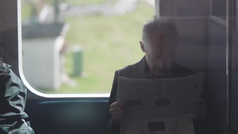 Japanese-Old-Man-Reading-The-Newspaper-On-The-Train-In-Tokyo,-Japan