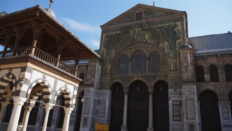 Tiro-Inclinado-Hacia-Arriba,-Que-Muestra-El-Diseño-De-La-Pared-Frontal-De-La-Mezquita,-Mujeres-Sirias-Con-Sus-Ropas-Tradicionales-Pasando