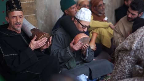 High-angle-closeup-of-men-in-Sufi-ceremony-playing-drums-and-chanting-in-Essaouira,-Morocco