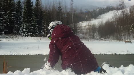 Child-plays-and-throws-snow-overlooking-ice-lake