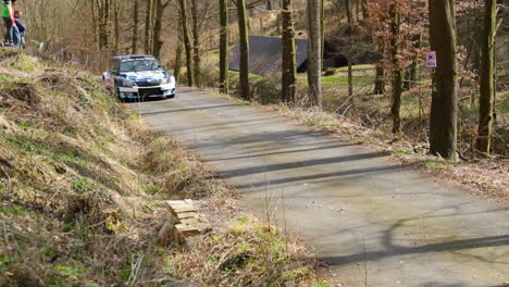 Vorbeifahrt-Eines-Skoda-Fabia-Rennwagens-Während-Einer-Valasska-Rallye-Zwischen-Bäumen-Auf-Einer-Asphaltstraße,-Wobei-Das-Auto-Steine-Und-Blätter-Zurücklässt,-Während-Es-Durch-Den-Wald-Fährt,-Aufgenommen-In-Zeitlupe-Mit-120-Bildern-Pro-Sekunde