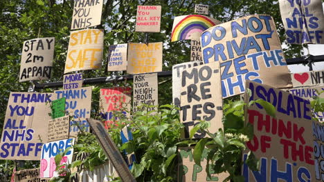 A-huge-memorial-wall-of-cardboard-signs-showing-support-of-healthcare-staff-and-all-other-key-workers-during-the-Coronavirus-outbreak-line-the-edge-of-a-park-in-the-East-End-of-London