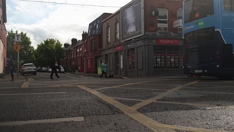 Panning-shot-of-a-Dublin-street-with-passing-by-and-people-queuing-outside-a-Lidl-store-and-vehicles